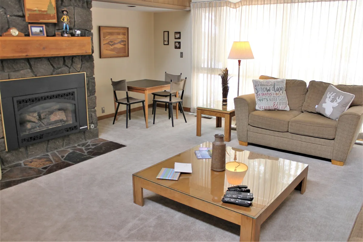 An inviting open-plan living and dining area with a fireplace, plush sofa, coffee table, dining table, and tasteful lighting. The flow between lounge and dining zones is evident, illustrating the seamless connection ideal for entertaining and relaxation.